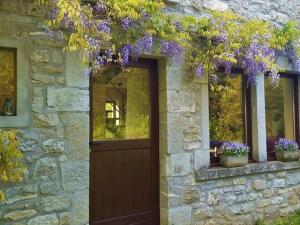 Una casa de piedra con una puerta con flores púrpuras. en Quaint Holiday Home in Robechies amid Meadows en Chimay