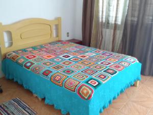 una cama con una colcha colorida en una habitación en Apartamento para casal. Perto do mar, en Tramandaí
