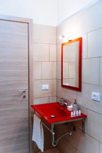 La salle de bains est pourvue d'un lavabo rouge et d'un miroir. dans l'établissement Casa Aragona b&b, à Capua