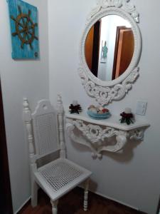 a mirror on a white wall with a chair and a table at CONDOMÍNIO ILHAS DO JUQUEHY in Sao Paulo