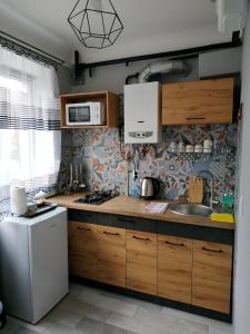 eine Küche mit Holzschränken und einem weißen Kühlschrank in der Unterkunft VEL Буковина in Czernowitz