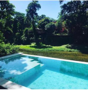 a swimming pool in front of a yard with trees at IN HOSPEDAGEM n45 in Paraty