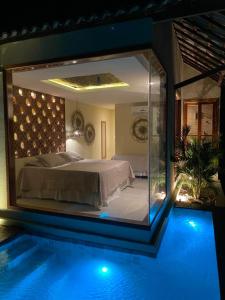 a bedroom with a large glass window next to a swimming pool at Vila do Alto - Beach Homes in Itarema