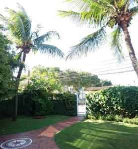 um jardim com duas palmeiras e um passadiço de tijolos em Pousada Bartrô em Rio das Ostras