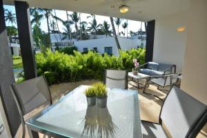 a glass table with a vase on top of a patio at Oasis Apartment C4 inside ALIGIO Residence Hotel in Las Terrenas