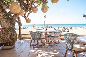 Kaimana Beach Hotel في هونولولو: فناء مع طاولة وكراسي والشاطئ