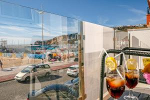 a balcony with two wine glasses and a view of a parking lot at Préstige Holidays Alojamentos in Nazaré
