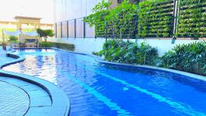 une grande piscine bleue à côté d'un bâtiment dans l'établissement One Pacific Place Serviced Residences, à Manille