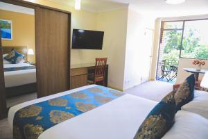 a hotel room with a bed and a desk with a television at Metro Inn Ryde in Sydney