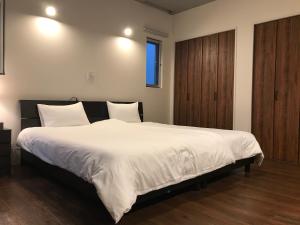 a bedroom with a large bed with white sheets at D-and Stay HH.Y Resort Okinawa in Teruya