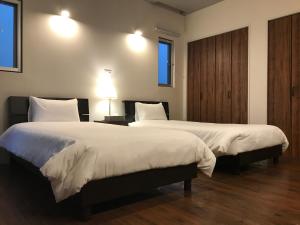 two beds in a hotel room with two lamps at D-and Stay HH.Y Resort Okinawa in Teruya