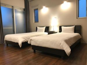 dwa łóżka w pokoju hotelowym z dwoma lampami w obiekcie D-and Stay HH.Y Resort Okinawa w mieście Teruya
