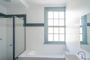 a white bathroom with a tub and a sink at Oasis on Beamish Hotel in Sydney