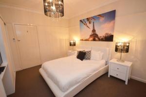 um quarto com uma cama branca e uma imagem da Torre Eiffel em No.40 Echuca - Echuca Holiday Homes em Echuca
