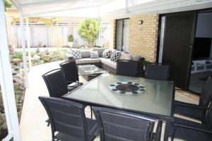 a patio with a table and chairs and a couch at Warnbro Beach Family Accommodation in Warnbro