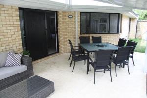 a patio with a table and chairs and a couch at Warnbro Beach Family Accommodation in Warnbro