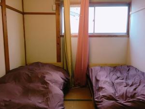 two beds in a room with a window at yado & kissa UGO HUB in Yuzawa