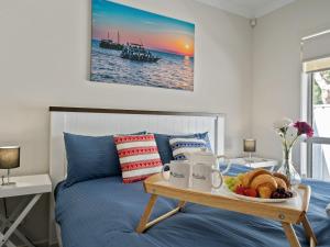 a breakfast tray on a bed with a tray of food at Adriatic Beach House in Callala Beach