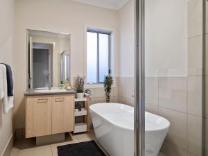 a white bathroom with a tub and a sink at Adriatic Beach House in Callala Beach