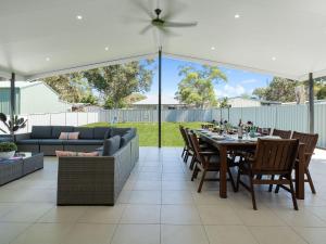 a patio with a table and chairs and a couch at Adriatic Beach House in Callala Beach