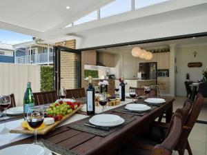 a dining room table with wine bottles and fruit on it at Adriatic Beach House in Callala Beach