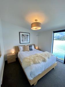 a bedroom with a large bed with a large window at 'LakeLife' Lake Front Apartment in Queenstown