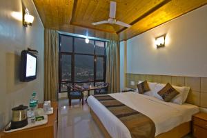 1 dormitorio con cama, mesa y ventana en Hotel Broadways Inn, en Manali