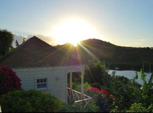 a house with the sun setting over a mountain at The Ocean Inn Antigua in English Harbour Town