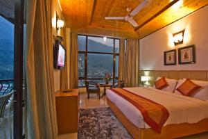 a bedroom with a bed and a large window at Hotel Broadways Inn in Manāli