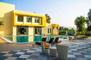 a house with a swimming pool with chairs and a building at The Bhagwati Resort in Ābu Road