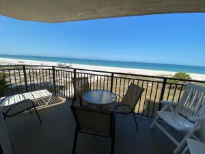 uma varanda com cadeiras e uma mesa e a praia em Vistas on the Gulf by Liberte' em St. Pete Beach