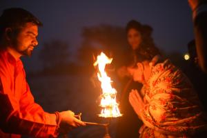 a man holding a torch and a woman holding a flame at Amatra By The Ganges in Haridwār