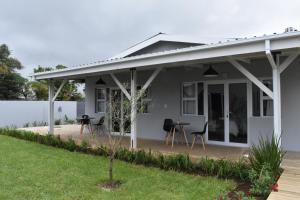 a white house with a patio and a table at Mosswood Bed & Breakfast in Graskop