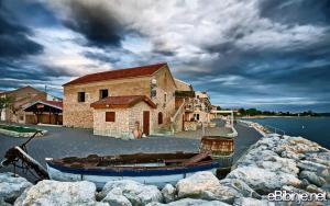 a boat sitting in the water next to a building at Apartman Viktorija in Bibinje