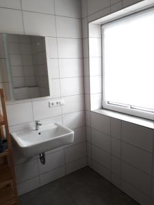 a white bathroom with a sink and a window at Schoppenstube May in Weigenheim