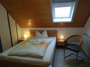 a bedroom with a bed and a chair and a window at Pension "Der Sulzbachhof" in Lehrberg