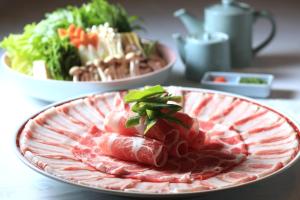 a plate of food with meat and vegetables on a table at SHIROYAMA HOTEL kagoshima in Kagoshima +66 photos