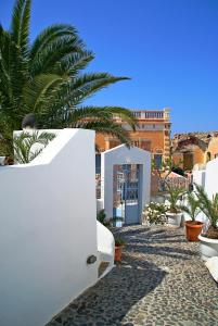een wit gebouw met een palmboom ervoor bij Aethrio Sunset Village - Oia in Oia