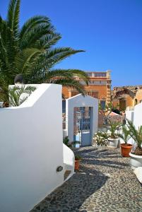 un bâtiment blanc avec un palmier en face dans l'établissement Aethrio Sunset Village - Oia, à Oia