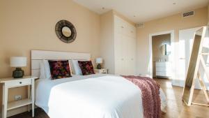 a bedroom with a white bed and a mirror on the wall at Magno Apartments San Martín Terrace in Seville