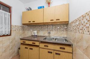 een keuken met een spoelbak en houten kasten bij Apartment Barbara in Batalaži +14 foto's