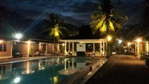una piscina frente a una casa por la noche en Lucia Cottages en Sukarame