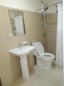 a bathroom with a sink and a toilet and a mirror at Thirdys Tourist Inn in Legazpi