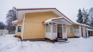 una casa con nieve en el suelo delante de ella en Hotel Aakenus Holiday Home Koivu, en Rovaniemi