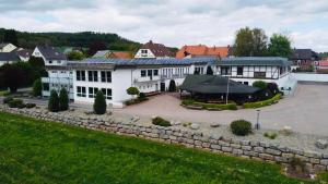 a large white building with a stone wall at Landhotel Weserblick in Beverungen