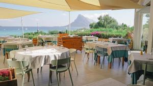 a restaurant with tables and chairs with a view of the ocean at Residence Hotel Lu Nibareddu in San Teodoro