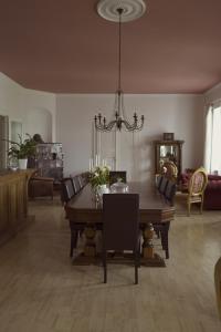 una sala da pranzo con tavolo, sedie e lampadario pendente di Boutique Hotel Le Baron a Găneşti