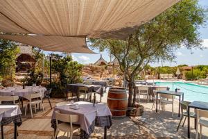a restaurant with tables and chairs and a pool at Residence Hotel Lu Nibareddu in San Teodoro