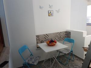 a small table with two chairs and a bowl of fruit at Casa Vacanze Fronte Mare Calasetta "CA' U CAPPUN" in Calasetta