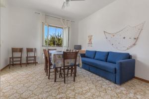sala de estar con sofá azul, mesa y sillas en Casa Bouganville by BarbarHouse, en San Pietro in Bevagna